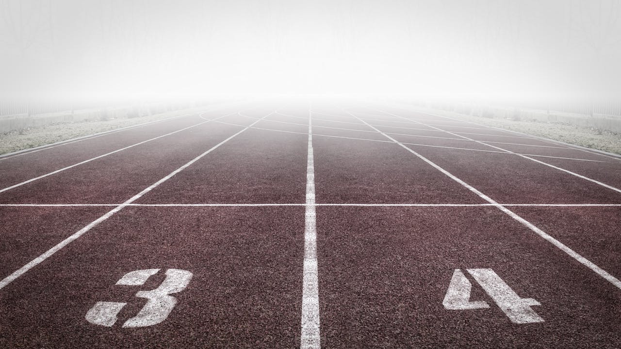 A foggy track field with visible lane numbers and white lines.